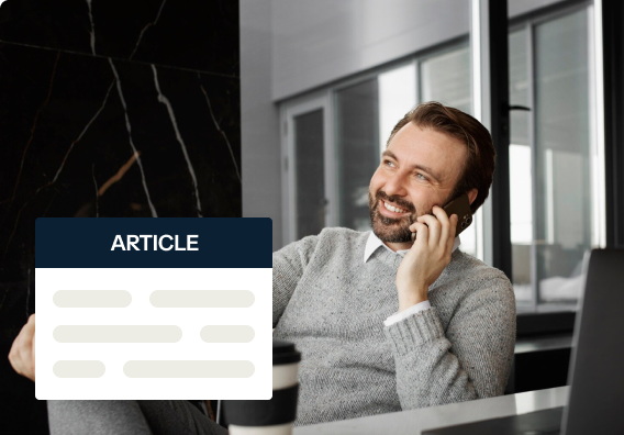 Man in a gray sweater sitting at a desk, smiling while talking on the phone. There is a cup beside him and a laptop partially visible. A stylized overlay with the word "ARTICLE" appears near him.